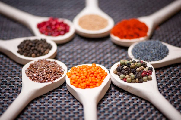 Various kind of spices on wooden spoon - detail of bean seeds — Stock Photo, Image