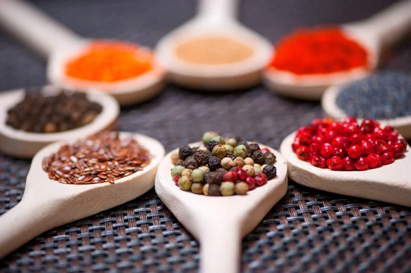 Various kind of spices on wooden spoon - detail of black, green and red pepper seeds — Stock Photo, Image