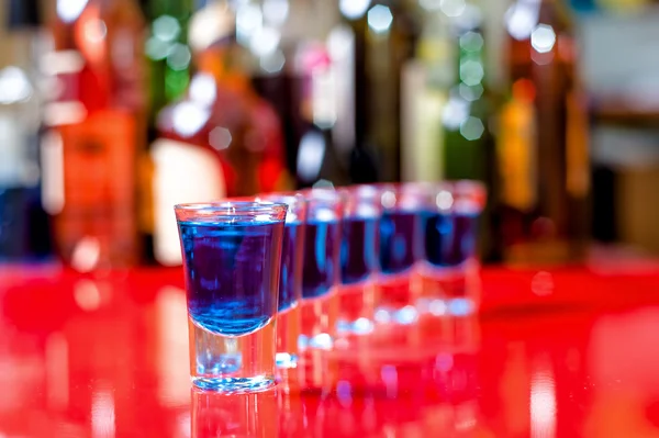 Row of shots on the counter with bar background, first is clear — Stock Photo, Image