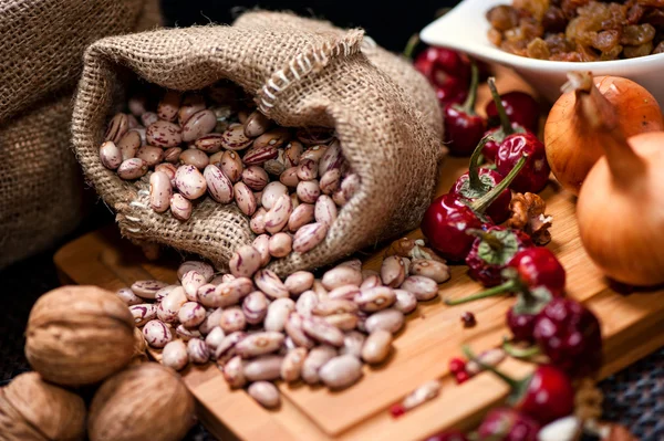 Bio-Zwiebeln, Nüsse, Bohnen und getrockneter Pfeffer als Lebensmittelzutaten auf dem Küchentisch — Stockfoto