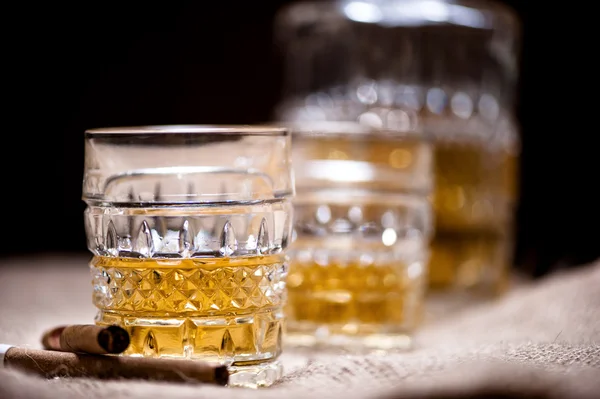 Whiskey in a glass on the rocks with bottle and vintage background — Stock Photo, Image