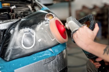 Otomotiv mühendisi bir araba otomobil Far parlatma onarım ve servis istasyonu, profesyonel güç arabellek makine kullanarak yenilemek