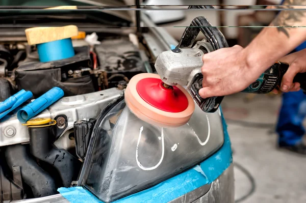 Conceito de cuidados com o carro com um mecânico limpando os faróis de um carro usando uma máquina tampão de energia na garagem especial — Fotografia de Stock