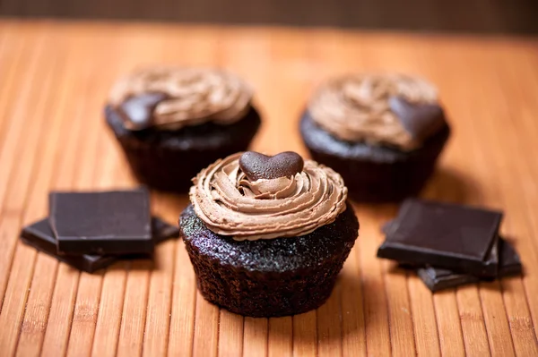 Close up of chocolate muffins and ingredients with sweet chocolate cream on top and a heart as a cookie — Stock Photo, Image