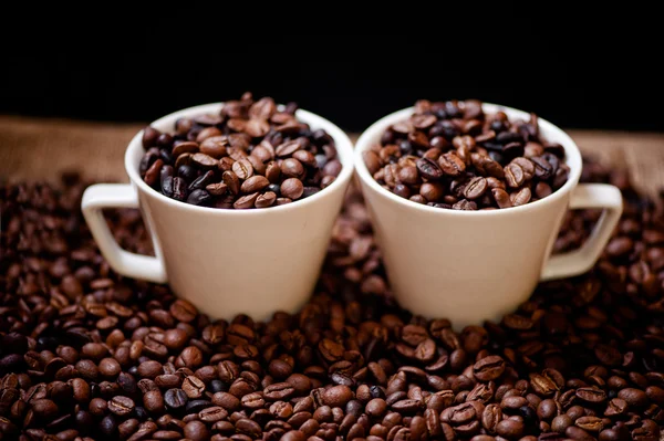 Frischer heißer kolumbianischer Kaffee in zwei Tassen, um Kaffeebohnen und Tuch — Stockfoto