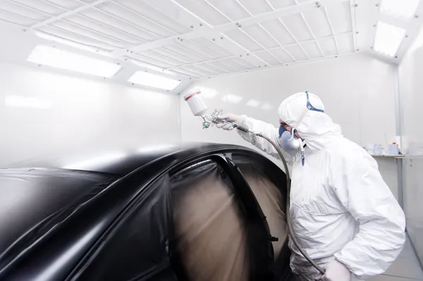 Ingeniero mecánico automotriz pintando el cuerpo de un coche negro —  Fotos de Stock