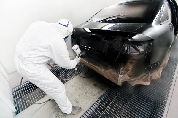 Travailleur peignant une voiture dans un garage à l'aide d'un pistolet aérographe — Photo