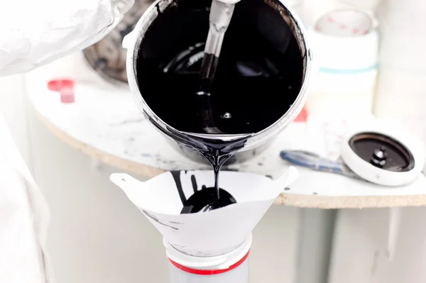 Mecánico preparando pintura negra para trabajar en un coche en garaje especial — Foto de Stock