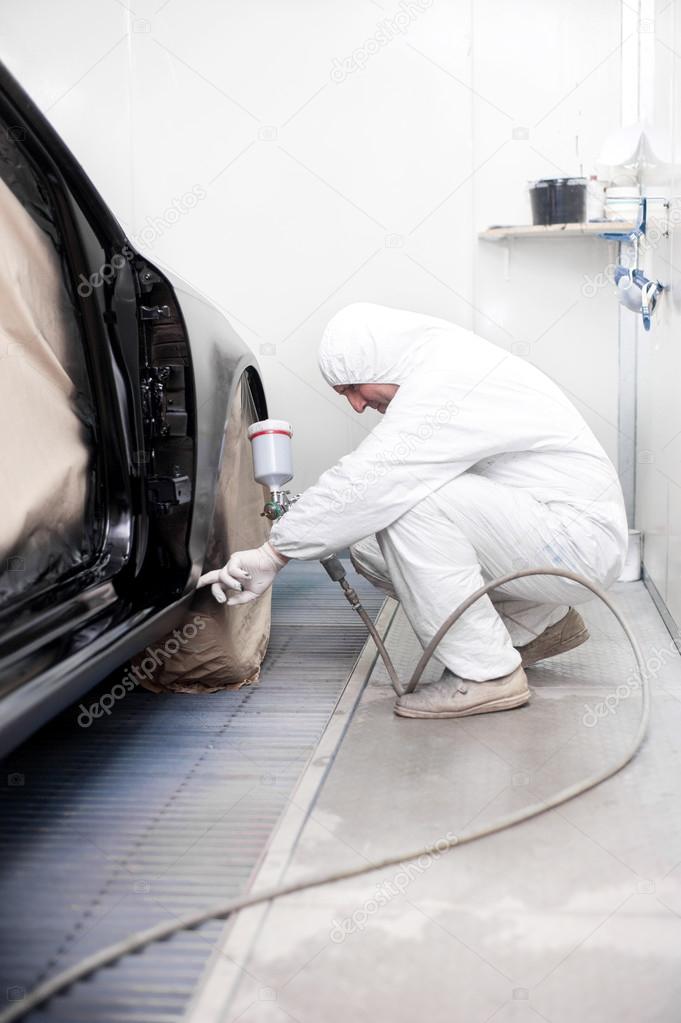 Automotive mechanical engineer painting the body of a black car Stock