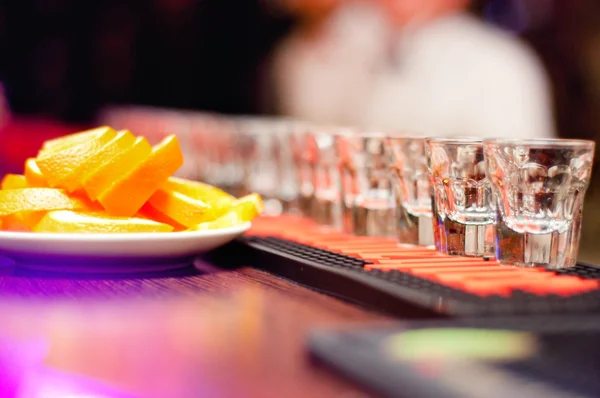 Alcoholic drinks in small glasses on the bar with orange — Stock Photo, Image