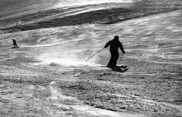 Silhueta de um esquiador salpicando neve enquanto liga a inclinação — Fotografia de Stock