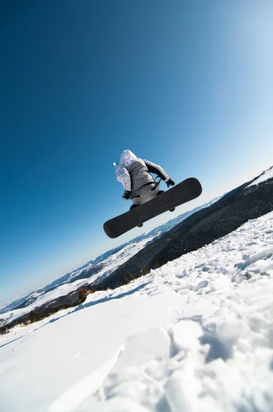 Snowboarder pulando na neve com fundo céu claro — Fotografia de Stock