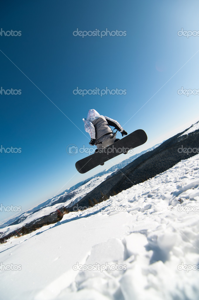 Snowboarder jumping in the snow with clear sky background