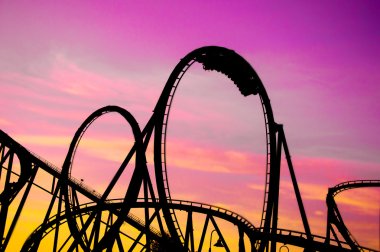 Colorful silhouette of a roller coaster at sunset, after a sunny