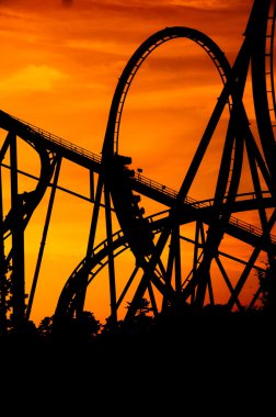 Silhouette of a roller coaster at a purple sunset with people on the ride clipart