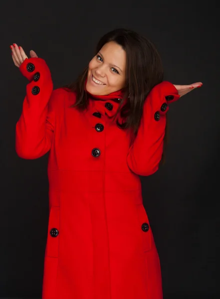 Молода приваблива брюнетка жіноча модель в червоному зимовому пальто і тримає її руки в повітрі — стокове фото