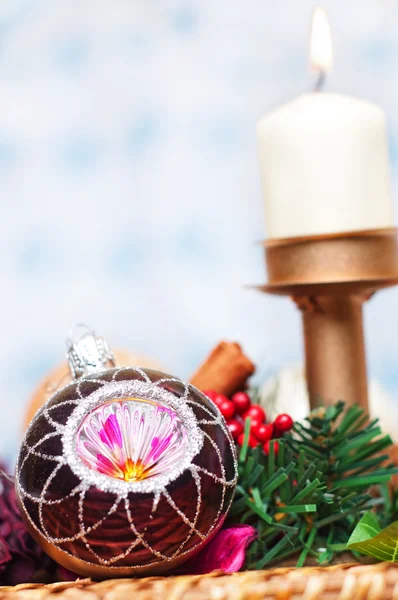 Bola de Navidad con pino, bayas y vela sobre fondo blanco y azul — Foto de Stock