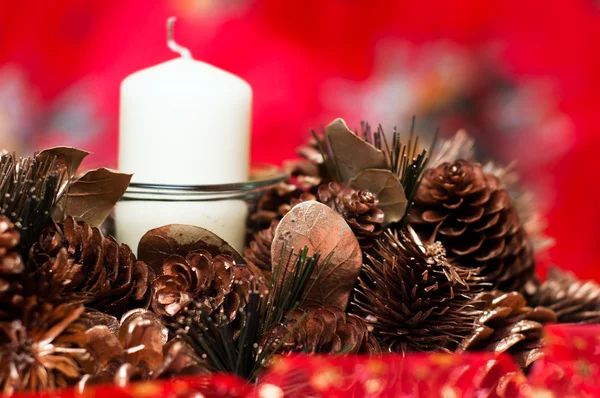 Corona de Navidad con vela, conos y oropel aislados sobre fondo rojo — Foto de Stock