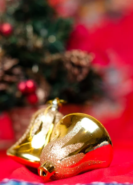 Two bell-shaped christmas balls with a christmas tree in the background — Stock Photo, Image