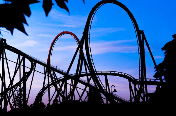 Entartaiment テーマ公園で楽しいフェア中に青い夕暮れ時のジェット コースターのシルエット — ストック写真