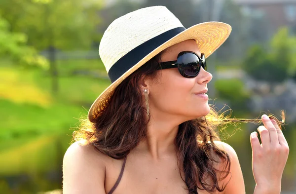 Retrato de una morena increíblemente sexy usando un bonito verano, sombrero rojo playa y gafas de sol mientras juega con su cabello —  Fotos de Stock