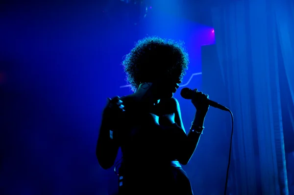 Silueta de una mujer cantando sobre fondo azul de discoteca — Foto de Stock
