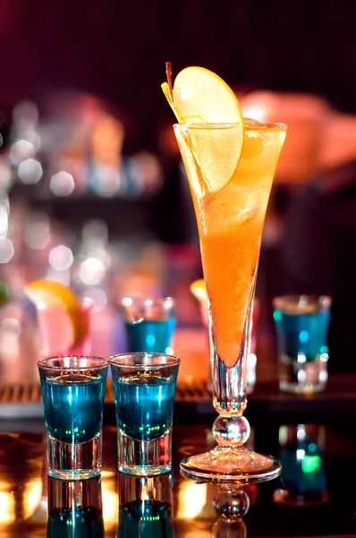Blaues, stark alkoholisches Getränk in kleinen Gläsern und ein Appletini an der Theke warten darauf, serviert zu werden — Stockfoto
