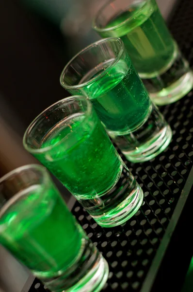 Zöld alkoholos folyadék a pultra állandó shot szemüveg — Stock Fotó