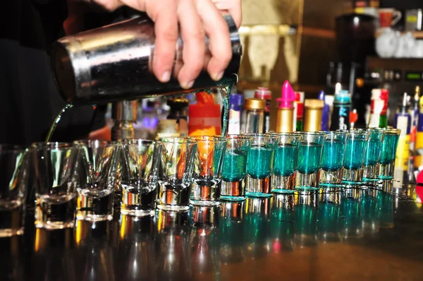Barman derrama bebida alcoólica em pequenos copos — Fotografia de Stock