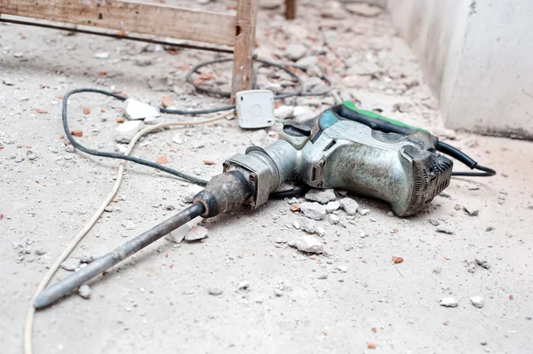 Ferramenta de construção, o martelo pneumático com detritos de demolição — Fotografia de Stock