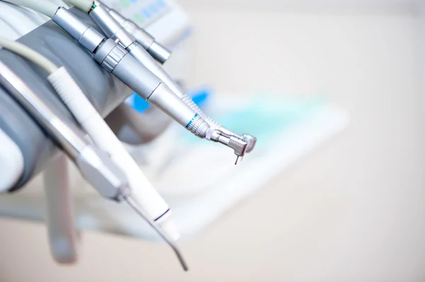 Ferramentas dentárias na cadeira de um dentista com fundo branco — Fotografia de Stock