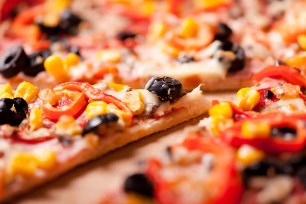 Close-up of slice of dinner pizza with ham, olives, mozzarella, pepperoni and tomatoes — Stock Photo, Image