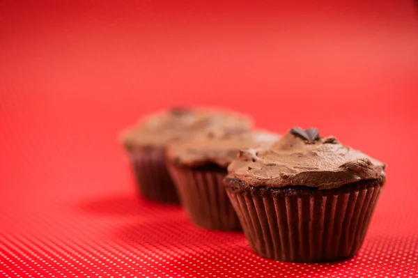 Primer plano de coloridas magdalenas rojas con cobertura de chocolate negro y helado —  Fotos de Stock