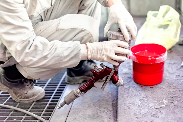 Промышленный рабочий готовит красную краску для распыления автомобиля в покрасочной кабинке — стоковое фото