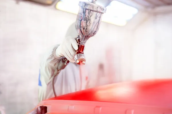 Close-up de pistola de pulverização e trabalhador pintando um carro — Fotografia de Stock