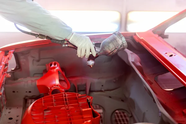 Lavoratore pittura un elemento auto, il cappuccio con vernice speciale e strumenti — Foto Stock