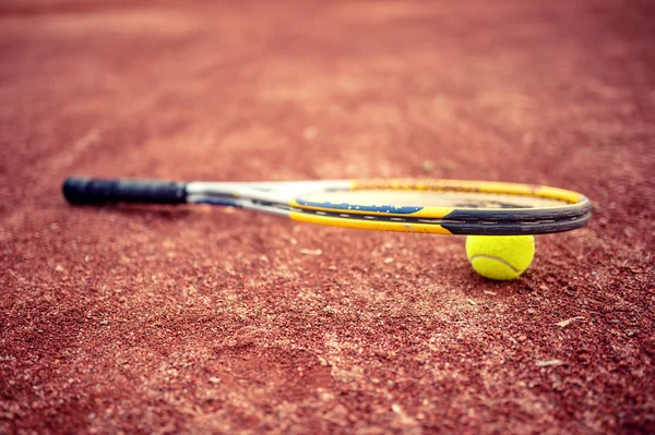 Close-up de raquete de tênis e bola na quadra de tênis de barro — Fotografia de Stock