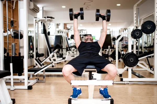 Jovem treinando no ginásio com haltere, exercício no banco torácico — Fotografia de Stock