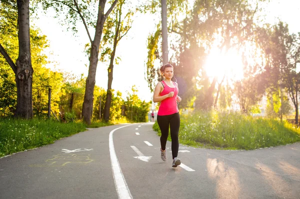 Portrait d'une coureuse active souriante, se reposant du jogging dans le parc au coucher du soleil — Photo