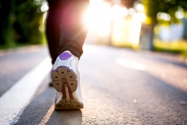 Närbild av idrottsman skor medan du kör i park. Fitness koncept med kvinnliga idrottare jogging i stadsparken — Stockfoto