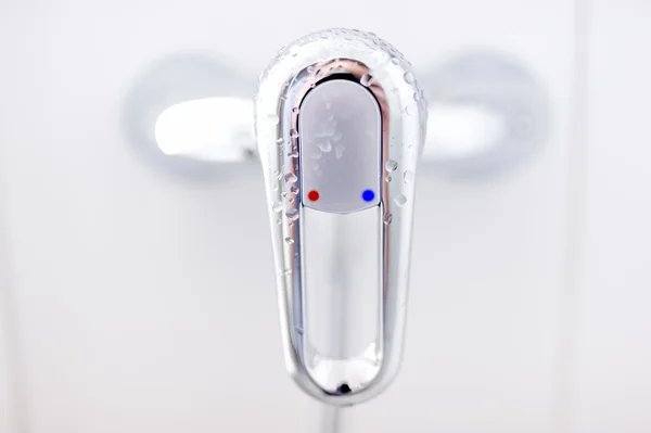 Close-up de torneira moderna do banheiro com símbolos de água e frio no fundo branco — Fotografia de Stock