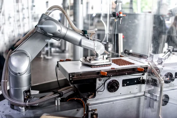 Automatische robotic hand verplaatsen en het voorbereiden van kleine stukjes van chocolade in chocolade fabriek. industriële chocoladefabriek met automatische robotic hand Rechtenvrije Stockfoto's