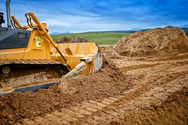Тяжелая загрузка бульдозеров и экскаваторов и перемещение красного песка или грунта на строительной площадке
