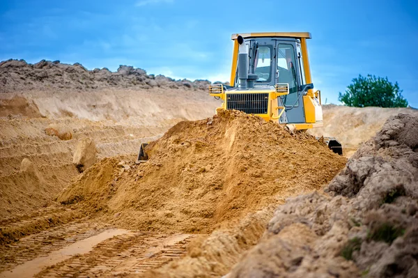 Industriële bulldozer en graafmachine werken met aarde in zandbak op snelweg bouwplaats — Stockfoto