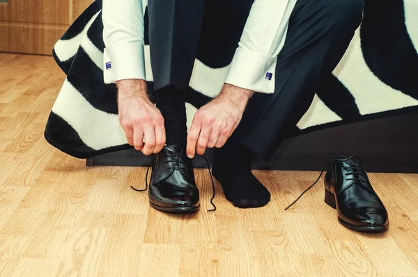 Novio usando zapatos el día de la boda, atando los cordones y preparándose. Hombre de negocios vestirse con zapatos clásicos y elegantes — Foto de Stock