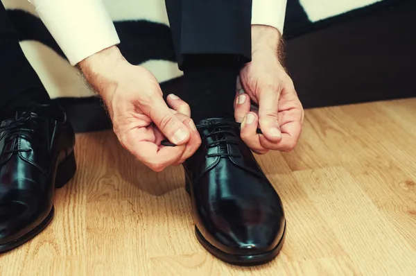 Hombre de negocios disfrazado con zapatos clásicos y elegantes. Novio usando zapatos el día de la boda, atando los cordones y preparándose. Efecto vintage — Foto de Stock