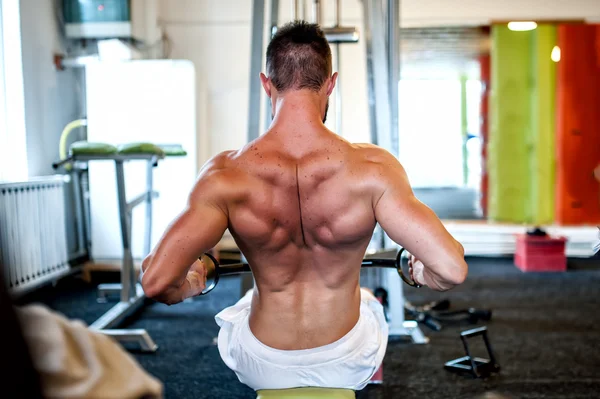 Gespierde man op dagelijkse workout routine in de sportschool, close-up van de rug oefening — Stockfoto