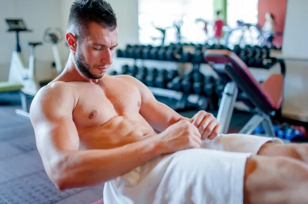 Musculoso hombre de entrenamiento en el gimnasio, ejercicios abdominales en el banco —  Fotos de Stock