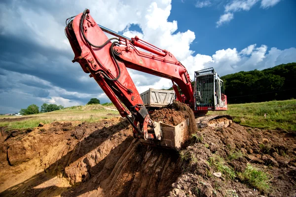 Excavatrice chargeant benne bascule camion benne dans le bac à sable sur le chantier de construction de l'autoroute et carrière — Photo