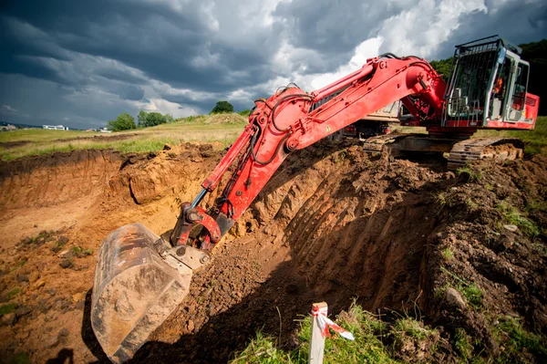 Промисловий екскаватор завантажує ґрунт з дорожньо будівельного майданчика — стокове фото